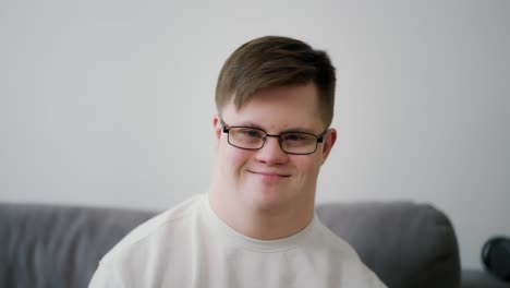 kind young man with down syndrome sitting on the sofa