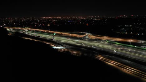 drone shot of night traffic on a motorway showing cars and lanes of light with tunnel and viaducts outside the city of warsaw, poland. moving the camera forward.