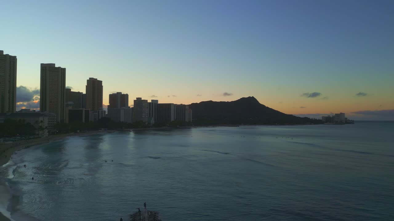 Drone aerial panoramic shot of Waikiki Beach in Oahu Island, Hawaii, at sunset with resorts, hotels and mountains in the background.