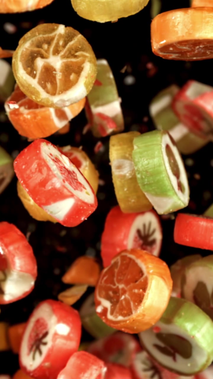 Bunte Fruchtbonbons fallen in Zeitlupe vor schwarzem Hintergrund