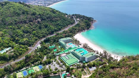 las imágenes de drones capturan un lujoso complejo marítimo en phuket, tailandia, que muestra aguas vibrantes de color turquesa y exuberante vegetación bajo la luz del día.