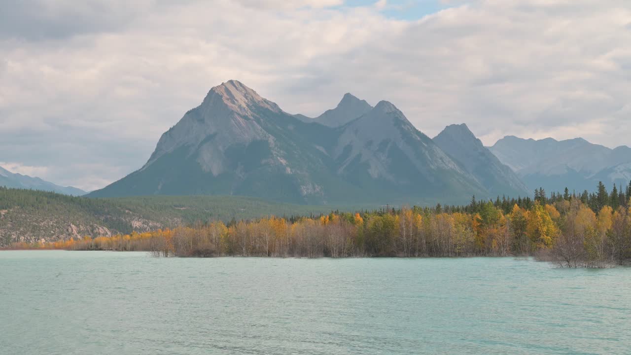 montañas con cielos nublados y abedules amarillos en otoño