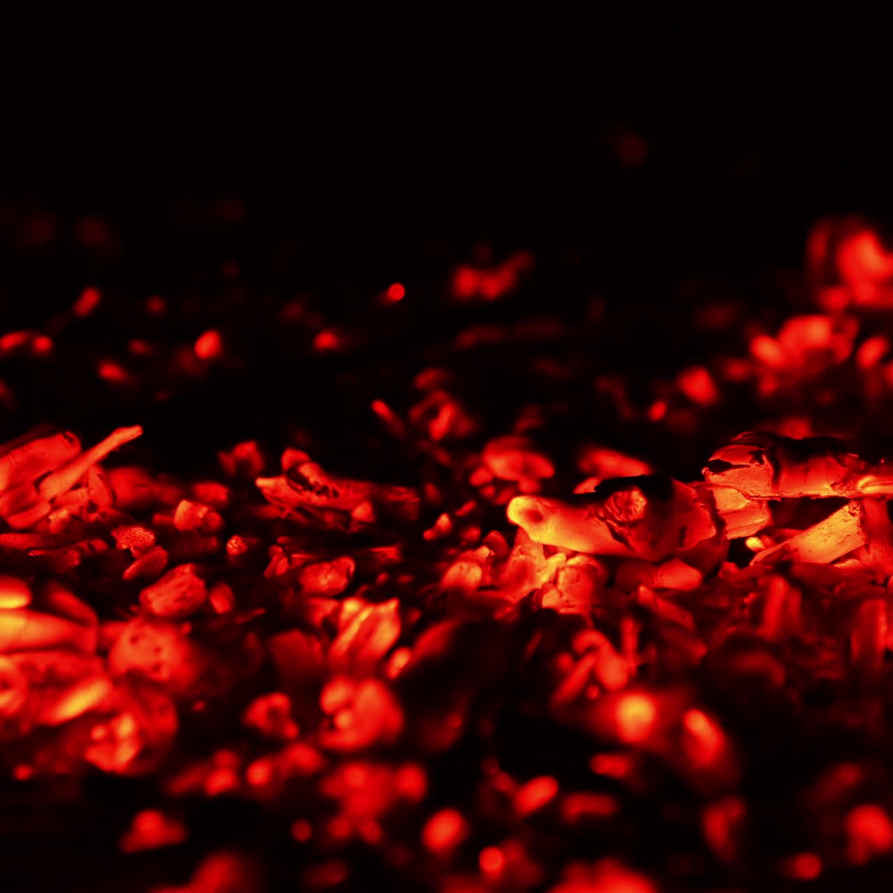 Red hot smoldering pieces of burnt out wood. Little fire flame splashes on the charcoal. Close up