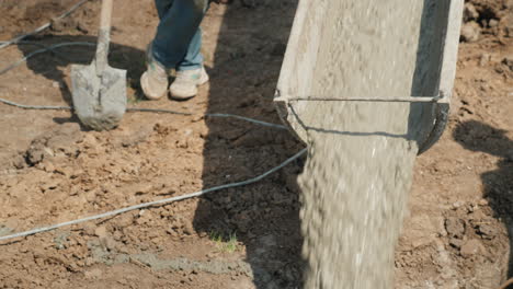 pouring concrete into the foundation from the gutter concrete flows next to the worker with a shovel