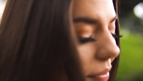 close up head shot of caucasian brunette young female blurry backround sharp focus on innocent eyes health and beauty slow motion