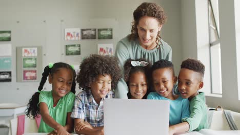 video of happy caucasian female teacher explaining lesson on laptop to diverse pupils