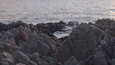 waves rolling into rocky cape at sunset in slow motion