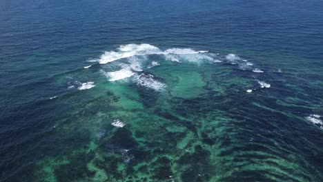 Aerial-drone-footage-of-the-waves-and-the-coral-reef-in-Lanzarote-island,-Spain