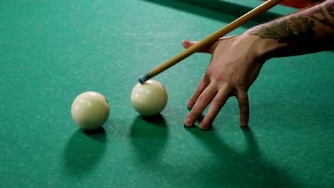 man playing pool in a dark bar, he hits the ball with a cue and hits the hole.