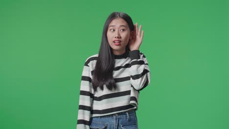 asian listening to something carefully while standing in front of green screen background