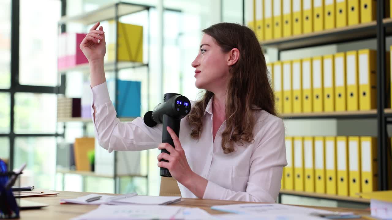 Woman using massage gun in office