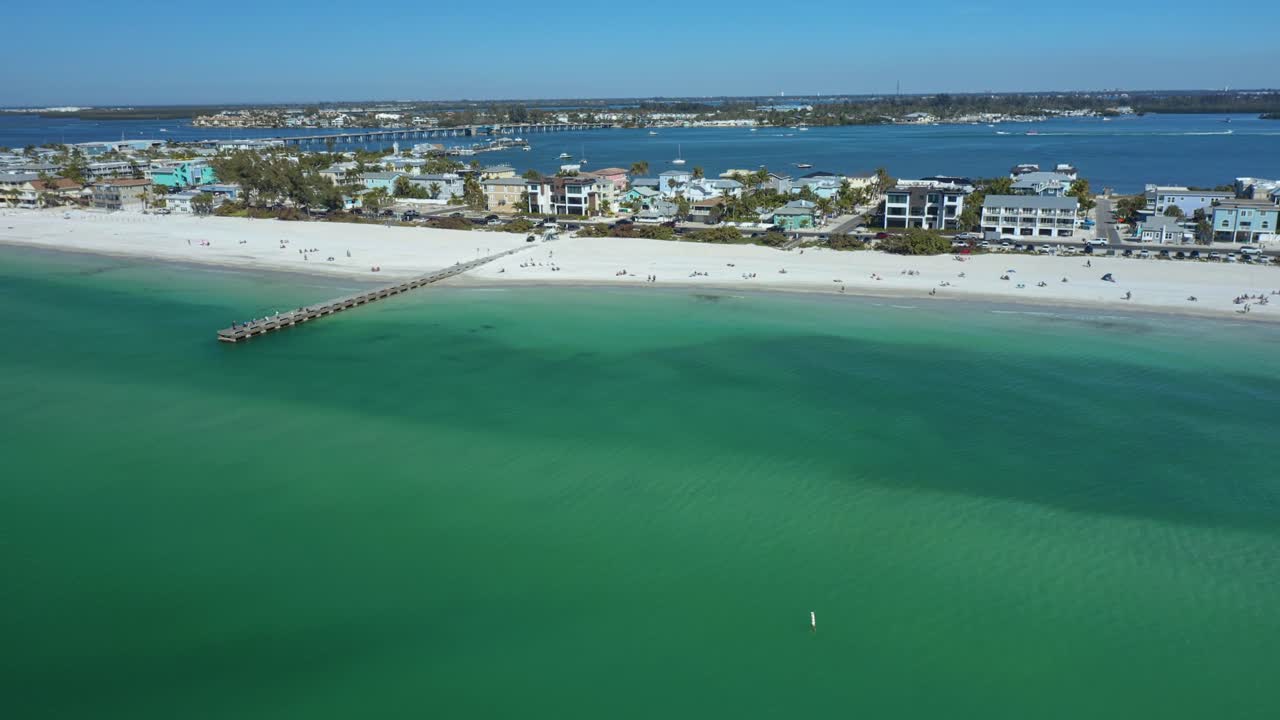 Riprese drone di Bradenton Beach che mostrano acque limpide color turchese e un litorale immacolato di sabbia bianca. Ideale per pubblicità di viaggi e promozioni turistiche.