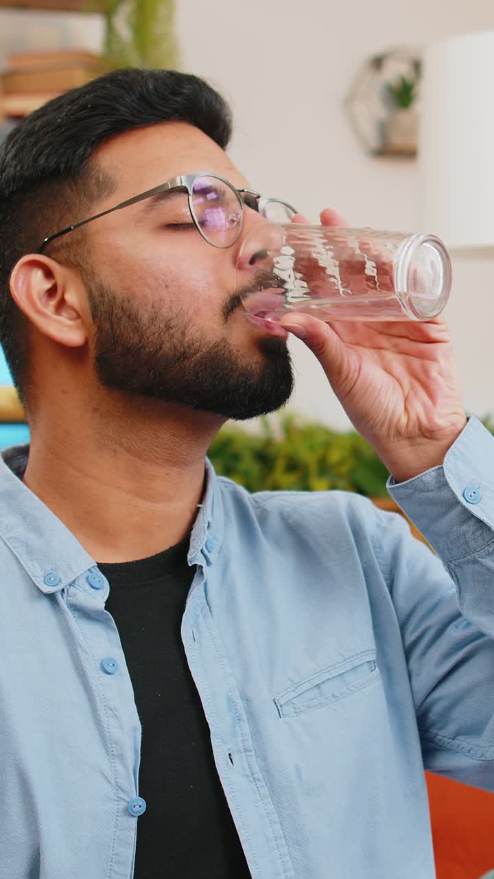indio enfermo hombre enfermo tomando medicamentos antibióticos píldora con agua en el sofá de la farmacia de atención médica