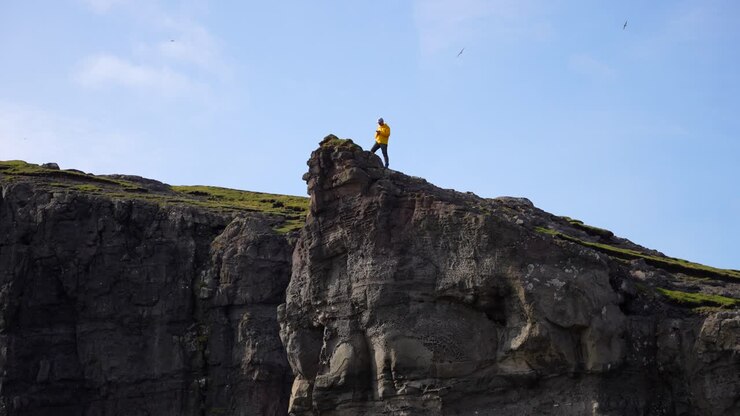 Man taking photo of Faroese landscape from Traelanipa cliff edge in Faroe Islands