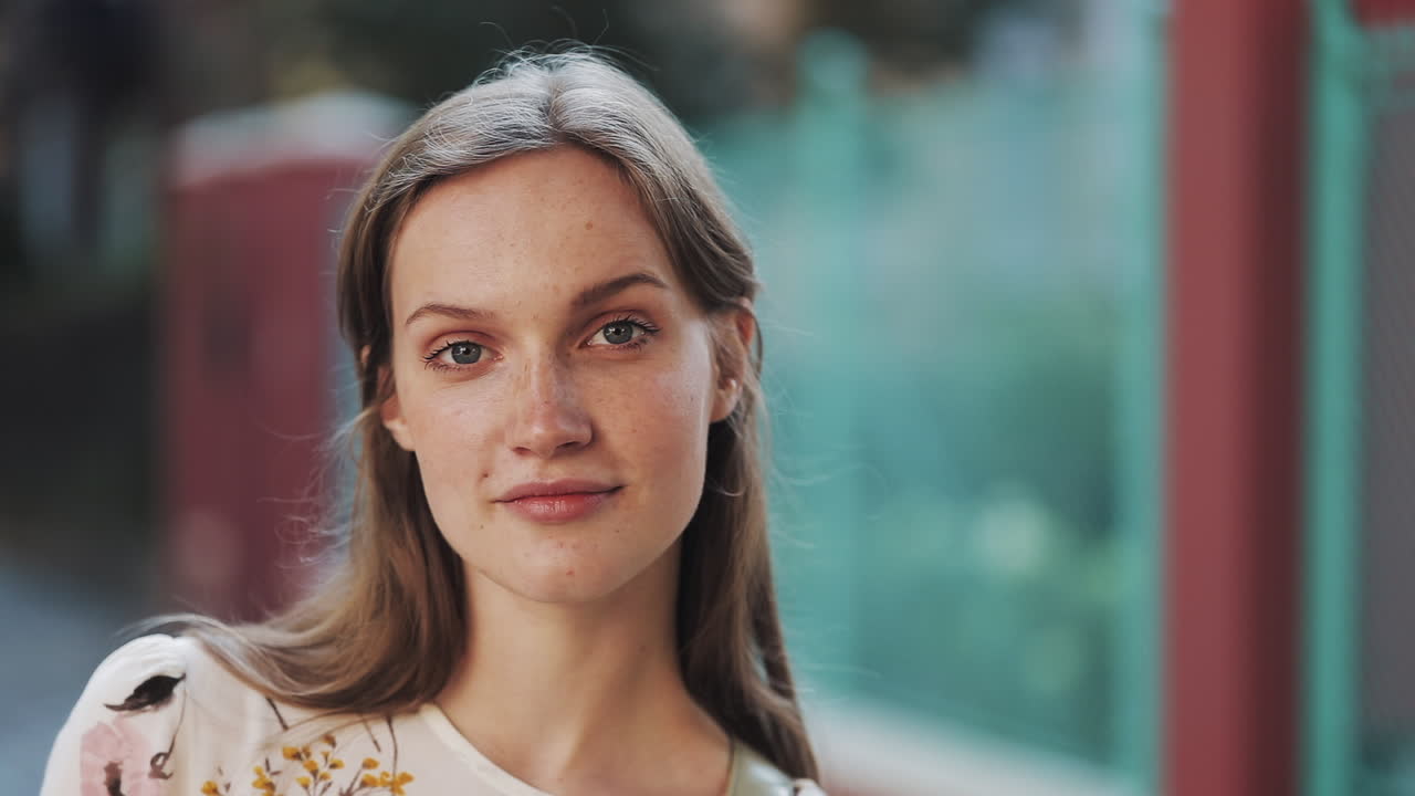 Mujer joven con pecas sonriendo y mirando a la cámara.