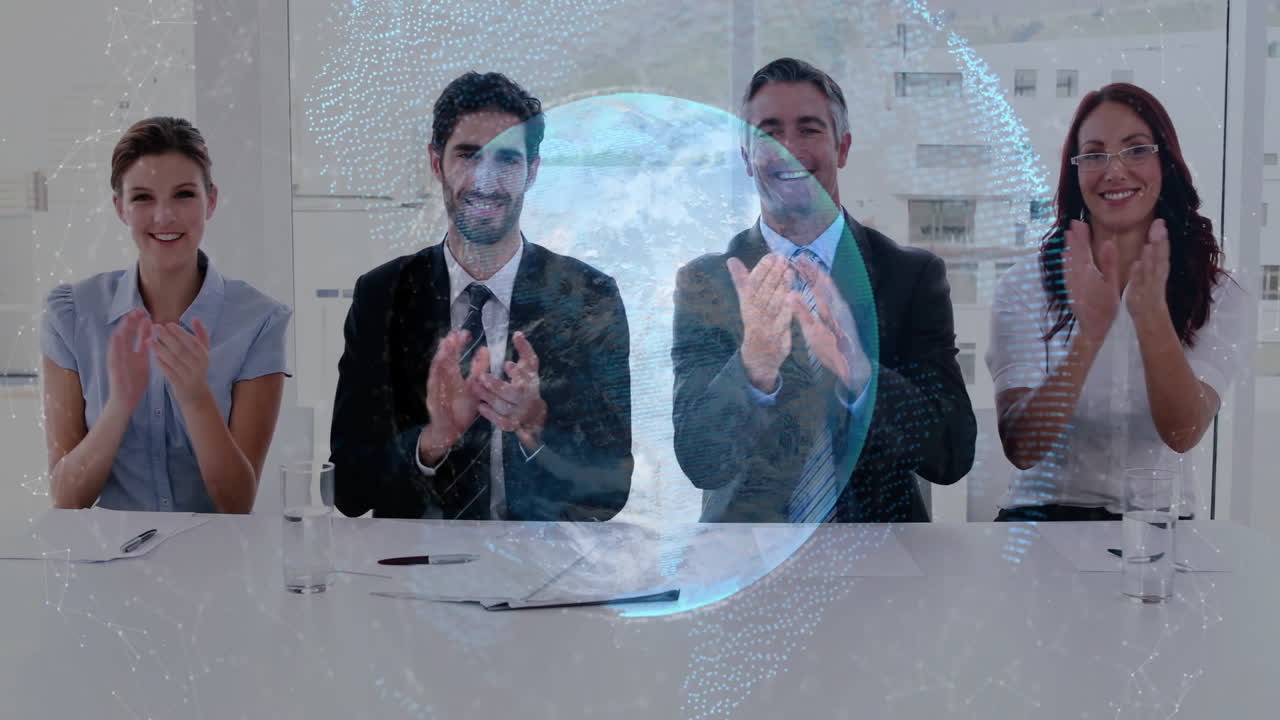 four professionals clapping around table, displaying digital globe hologram in business meeting