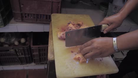 chef hands with knife cut chicken fillet meat on board in kitchen hands cutting fresh chicken meat on chopping board in the kitchen - close up butcher knife