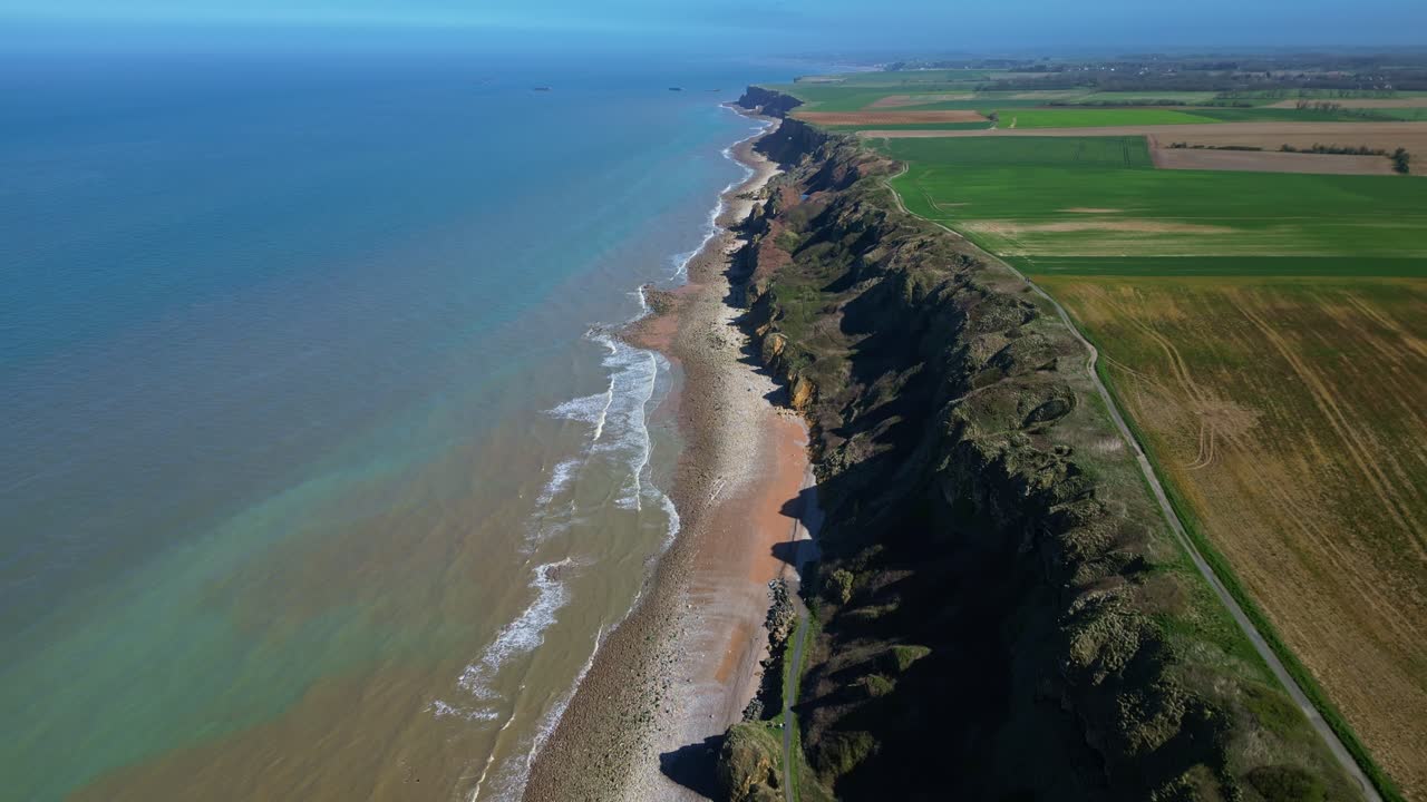 Coastal cliffs and sea at Longues-sur-Mer, Normandy, France. Aerial drone backward