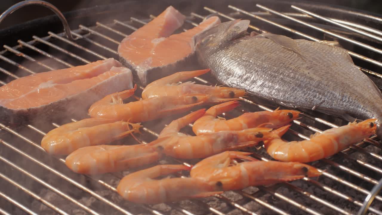 Chef cooking shrimps with oil and spices on grill close-up. Prawns on fire throwing them on pan. Dorado and salmon fish steak on frying grill. Restaurant Food concept. Sea food barbecue.