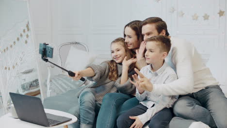 smiling family making victory gesture in front of mobile in luxury house