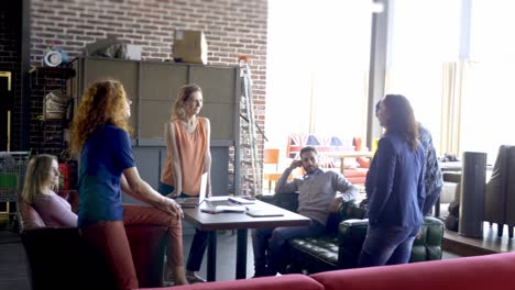concepto de negocios, startups y personas - equipo creativo feliz con computadoras y carpetas discutiendo proyectos en un espacio compartido en el loft.