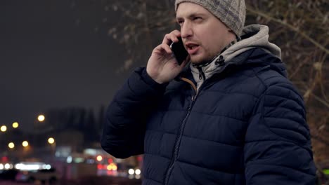 man receives a serious phone call standing outdoors in the city, handheld view with copy space