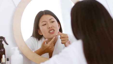 woman checking for acne in the bathroom