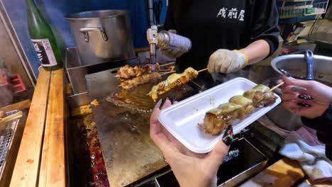 vendor pours sauce over meat skewers for customer