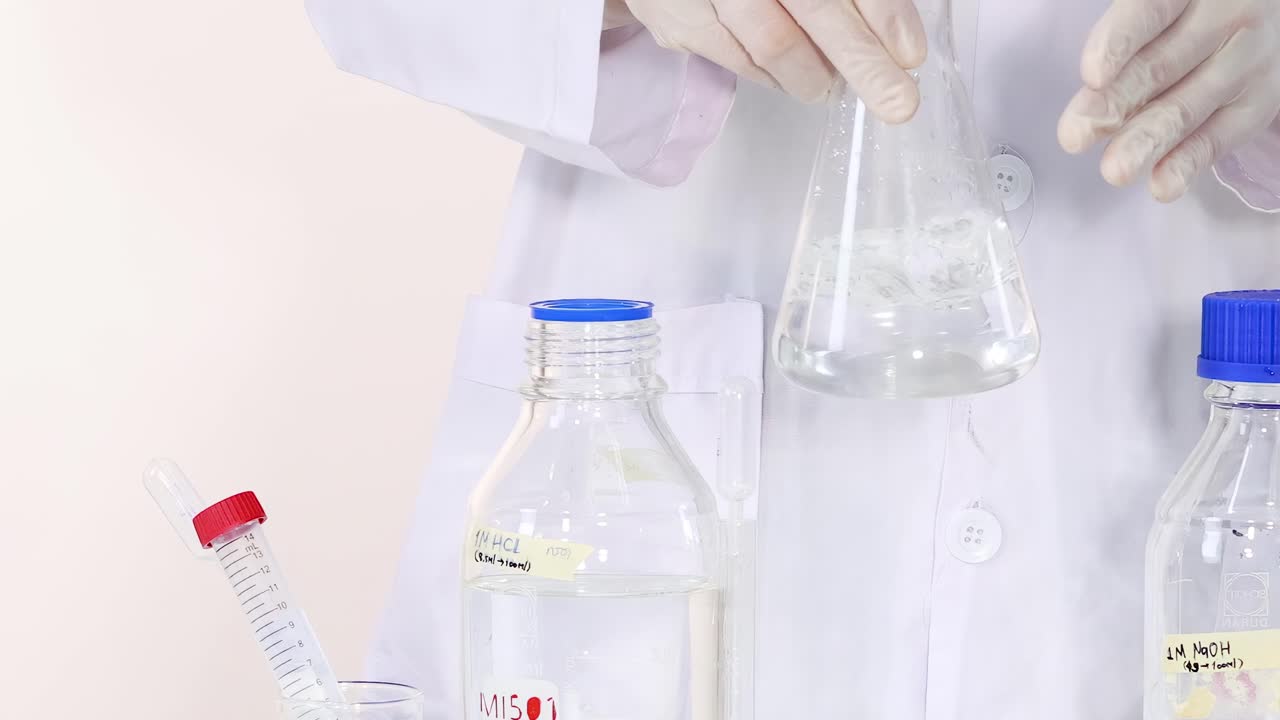 Observe the color change from pink to clear in a flask during a laboratory experiment.