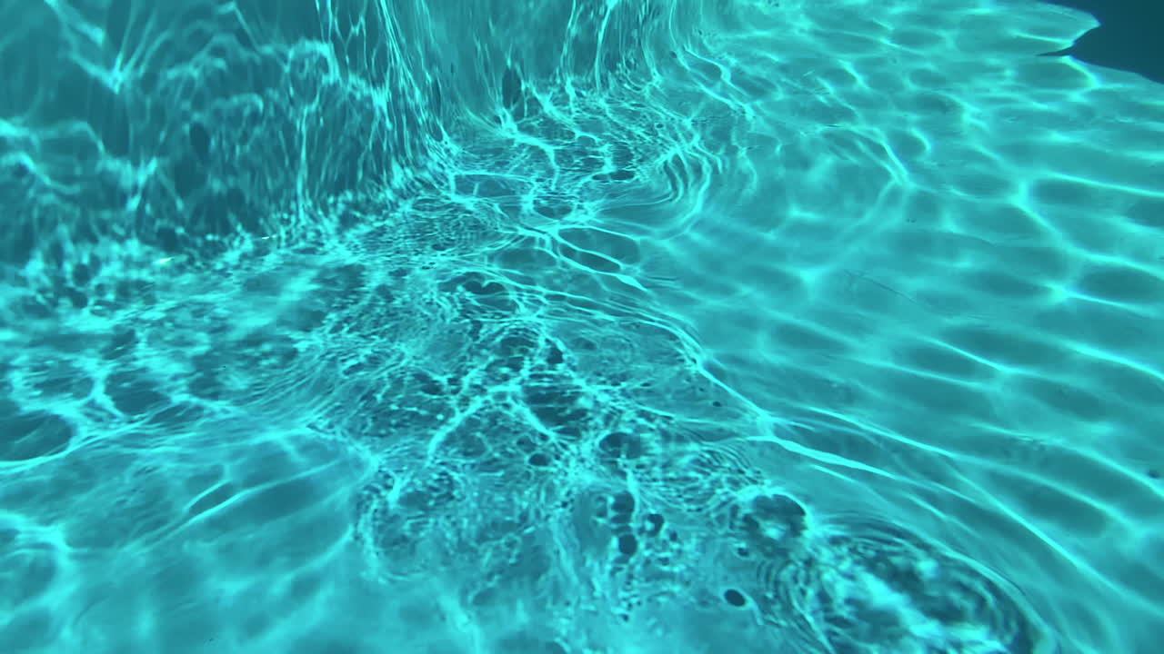 Rallentatore subacqueo di luce che si riflette sul fondo di una piscina in primo piano