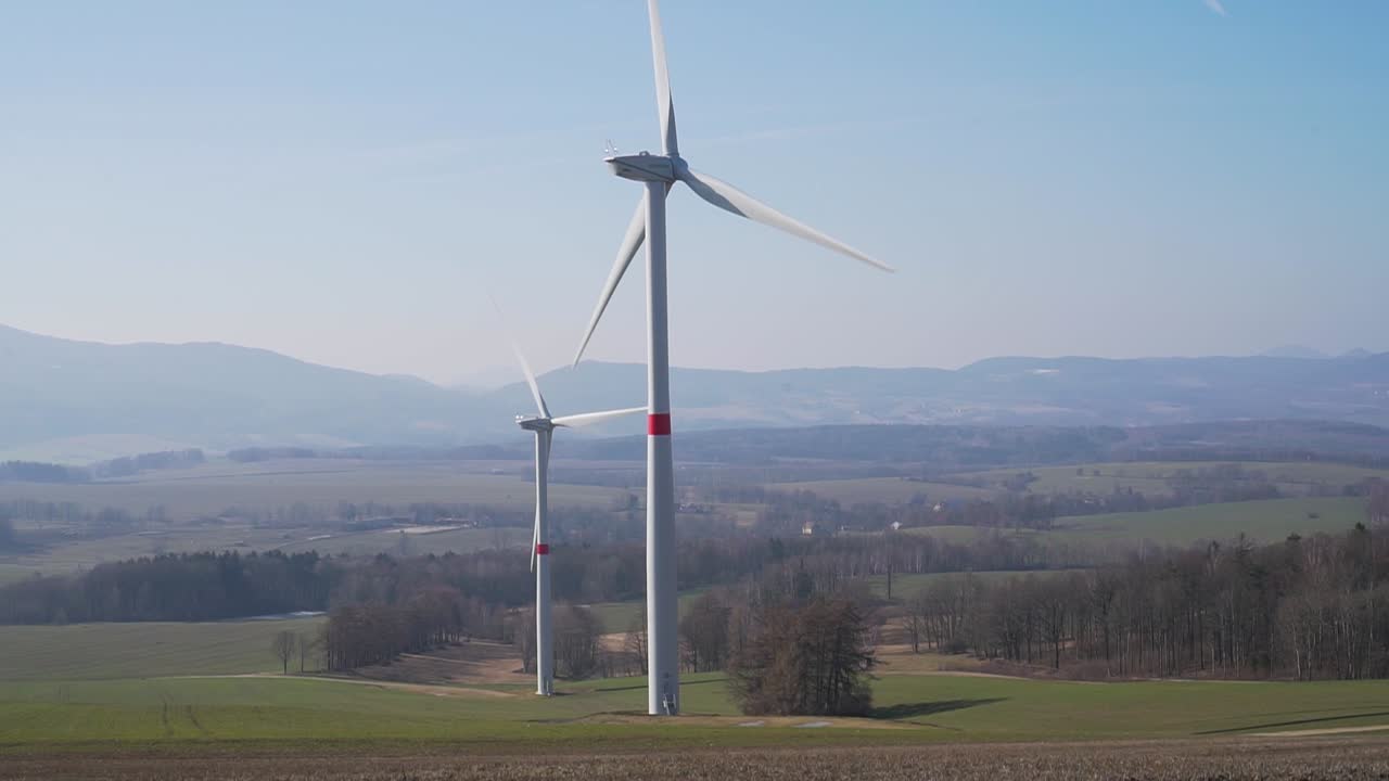Turbine eoliche in un campo con colline sullo sfondo - ripresa panoramica - SLOW MOTION