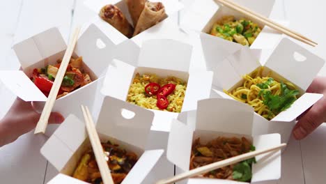 various oriental dishes packed in paper box  food is delivered on the table  asian take away concept