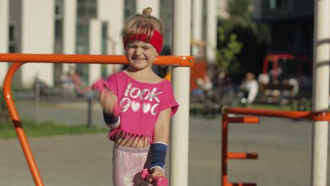 Caucasian-girl-in-sportswear-making-exercises-with-dumbbells.-Workout-for-kids.-Athletic-child