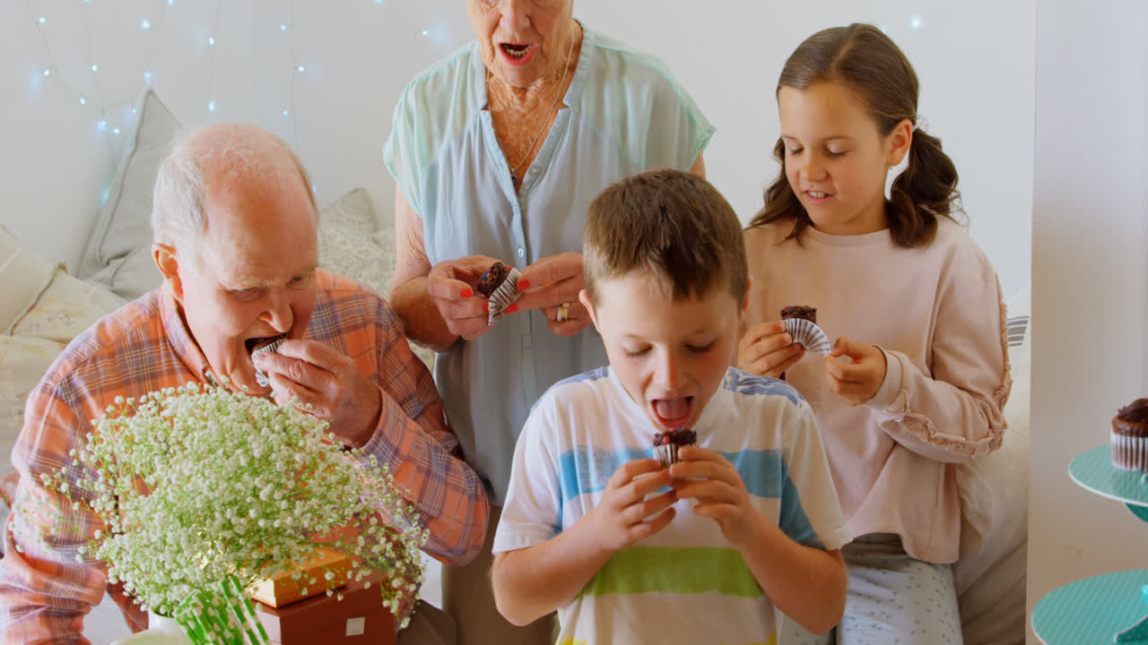 vista frontal de una familia caucásica de varias generaciones comiendo cupcakes en un hogar cómodo 4k
