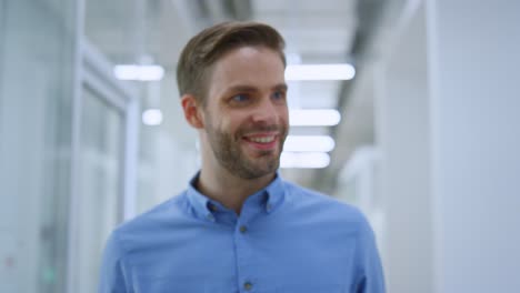 vista de cerca del guapo hombre de negocios que va a lo largo del corredor de la pared de vidrio