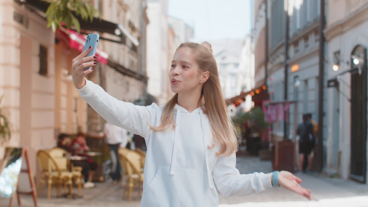 mujer joven caucásica chica turista hablando video chat hablando llamada telefónica teléfono inteligente en la calle de la ciudad