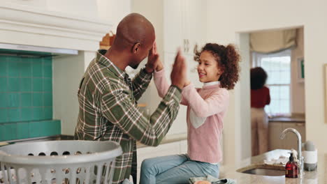 a father and daughter share a high five in their kitchen