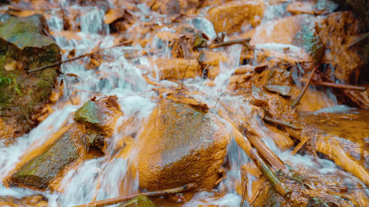 Zoom in shot of beautiful orange color rocks in a sulfur spring waterfall. Iron-containing water.