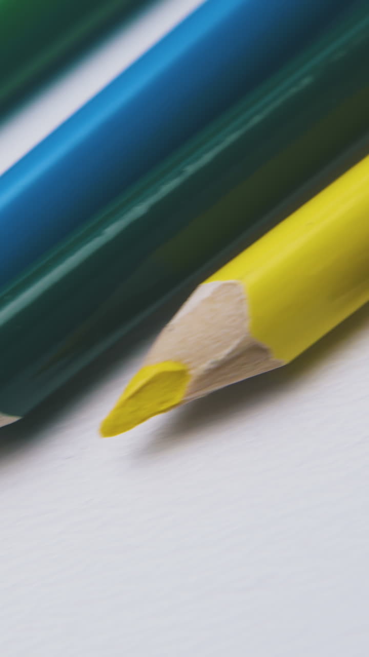 motion along row of bright colored pencils lying on clean white background extreme close view