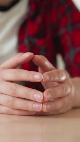 woman taps clasped fingertips at table closeup. young employee worries at meeting with supervisor in office. nervous lady with mental state disorder