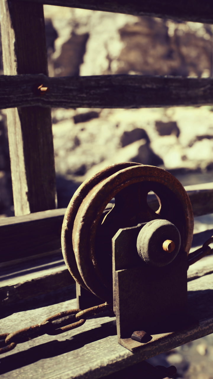 Old pulley mechanism resting against weathered wood by the riverbank at sunset