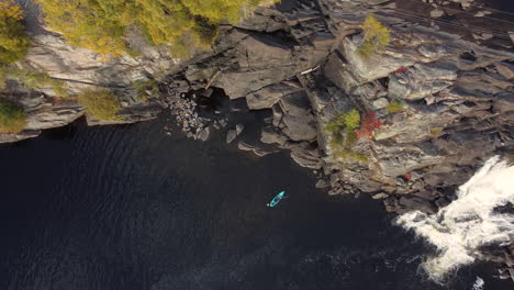 kayaker on muskoka river during autumn in ontario with high falls revealed