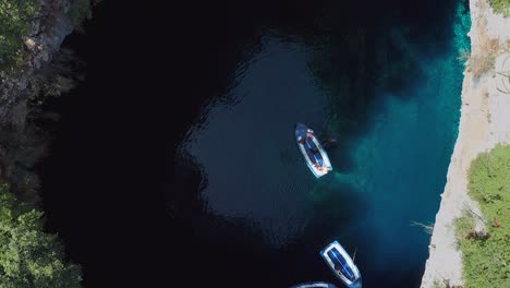 aerial top down view boat tour on melissani cave, crystal clear water, greece