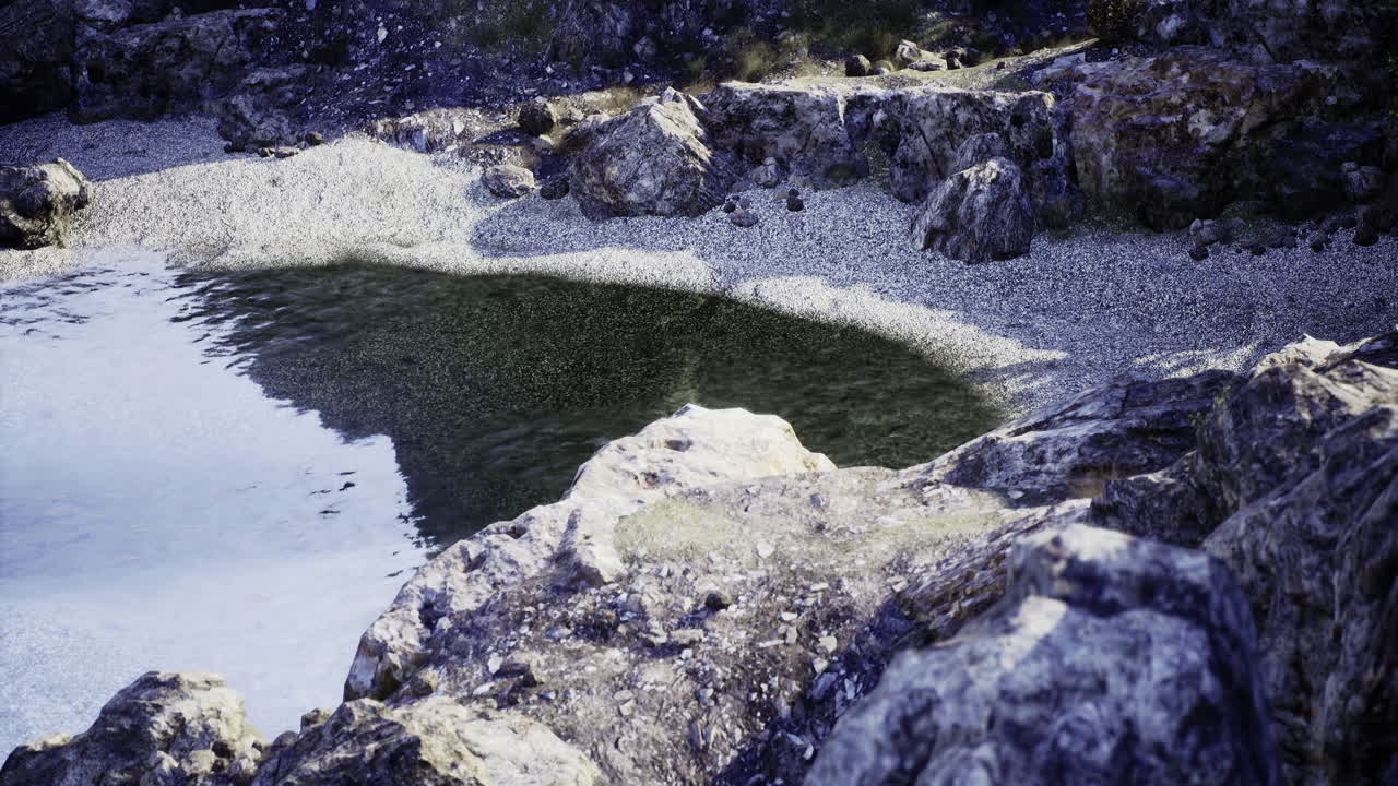 Serene rocky shoreline at a tranquil pond during golden hour