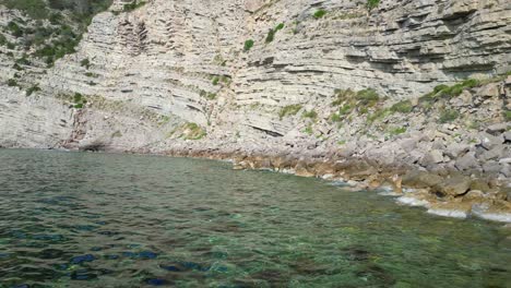 transparent turquoise water flows between rocks in a bay in ibiza, spain. beautiful aerial view flight dolly right drone