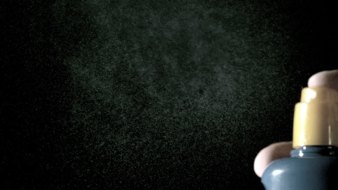 Hand using spray bottle of sun cream close up