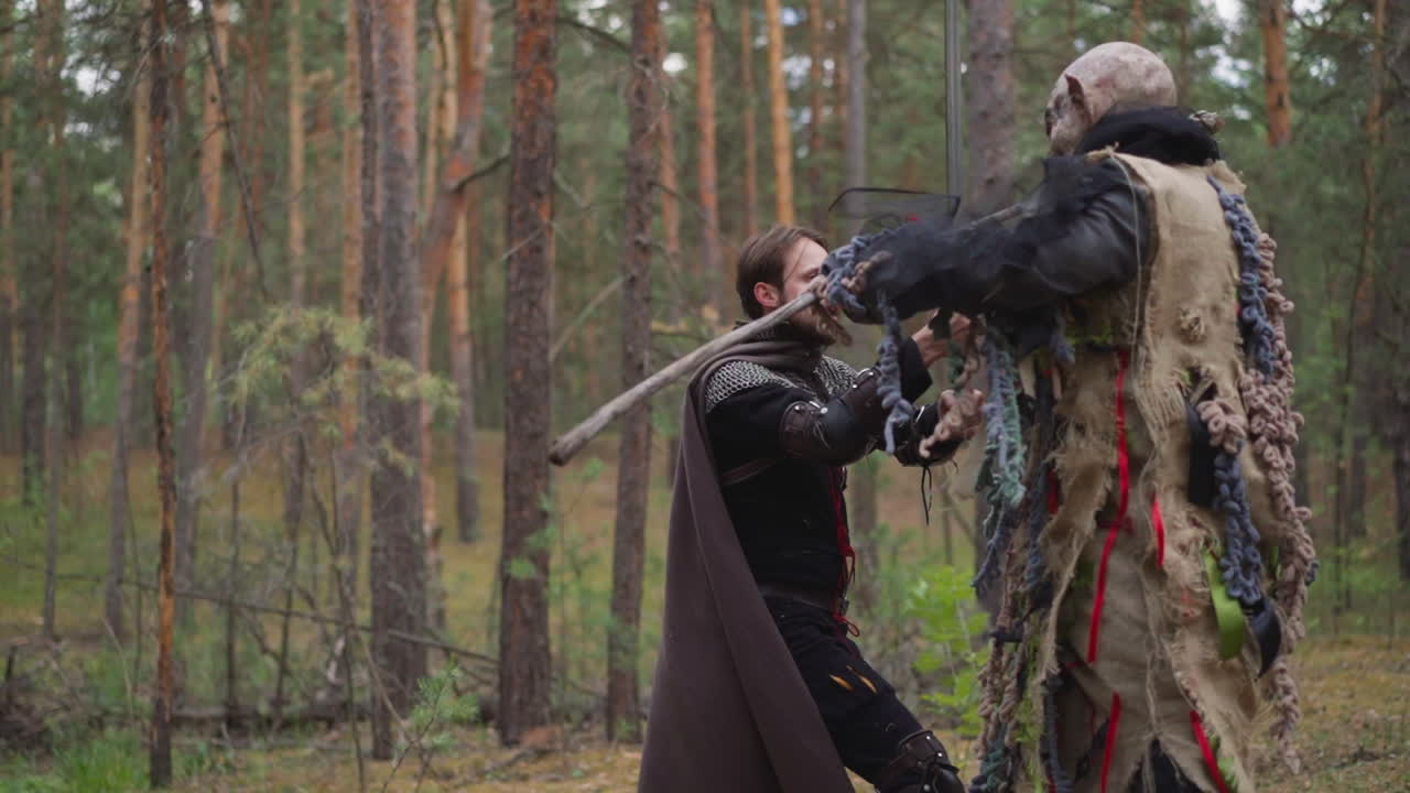 рыцарь падает после удара монстра в хвойном лесу.