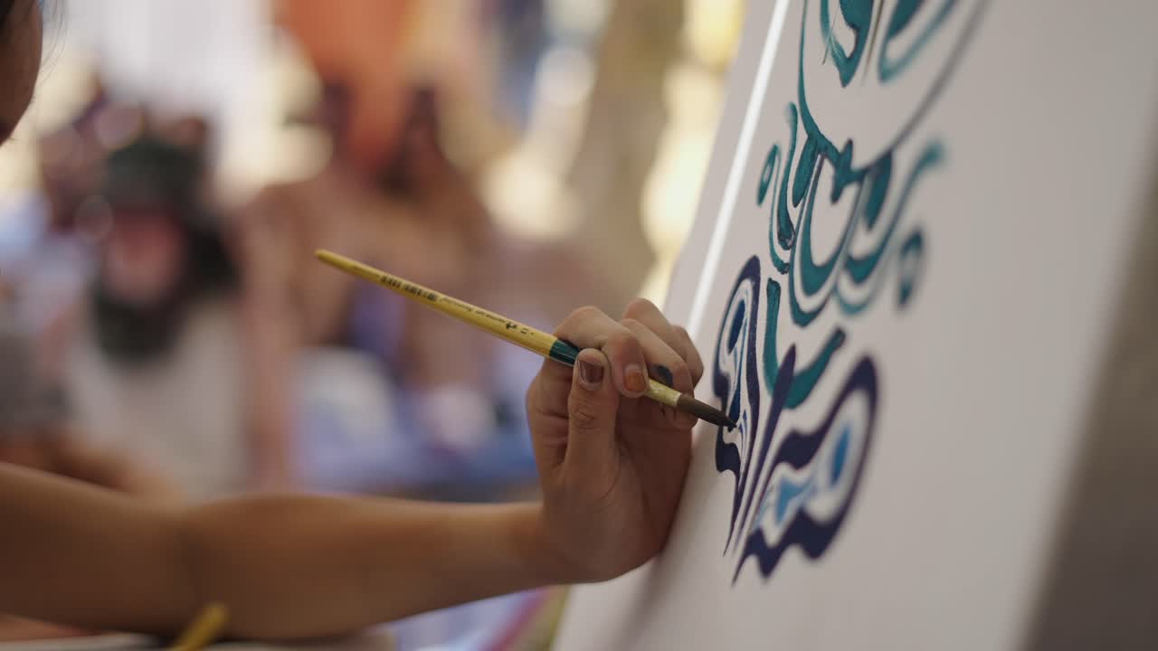 Close-up of a hand painting intricate designs on a canvas