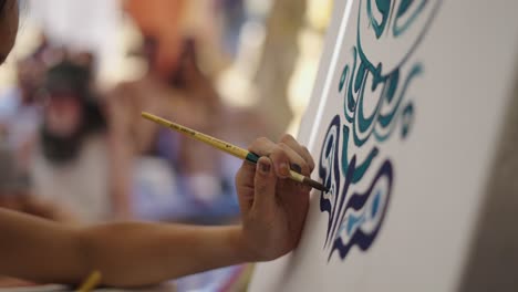 close-up of a hand painting intricate designs on a canvas