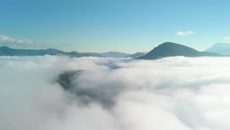 cockpit view flying through the clouds, sea of mist with mountains peaking through, mountain valley early morning, thick cloud cover in the mountain valley